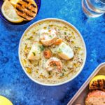 A bowl of hearty seafood chowder with grilled lemon and toasted bread.