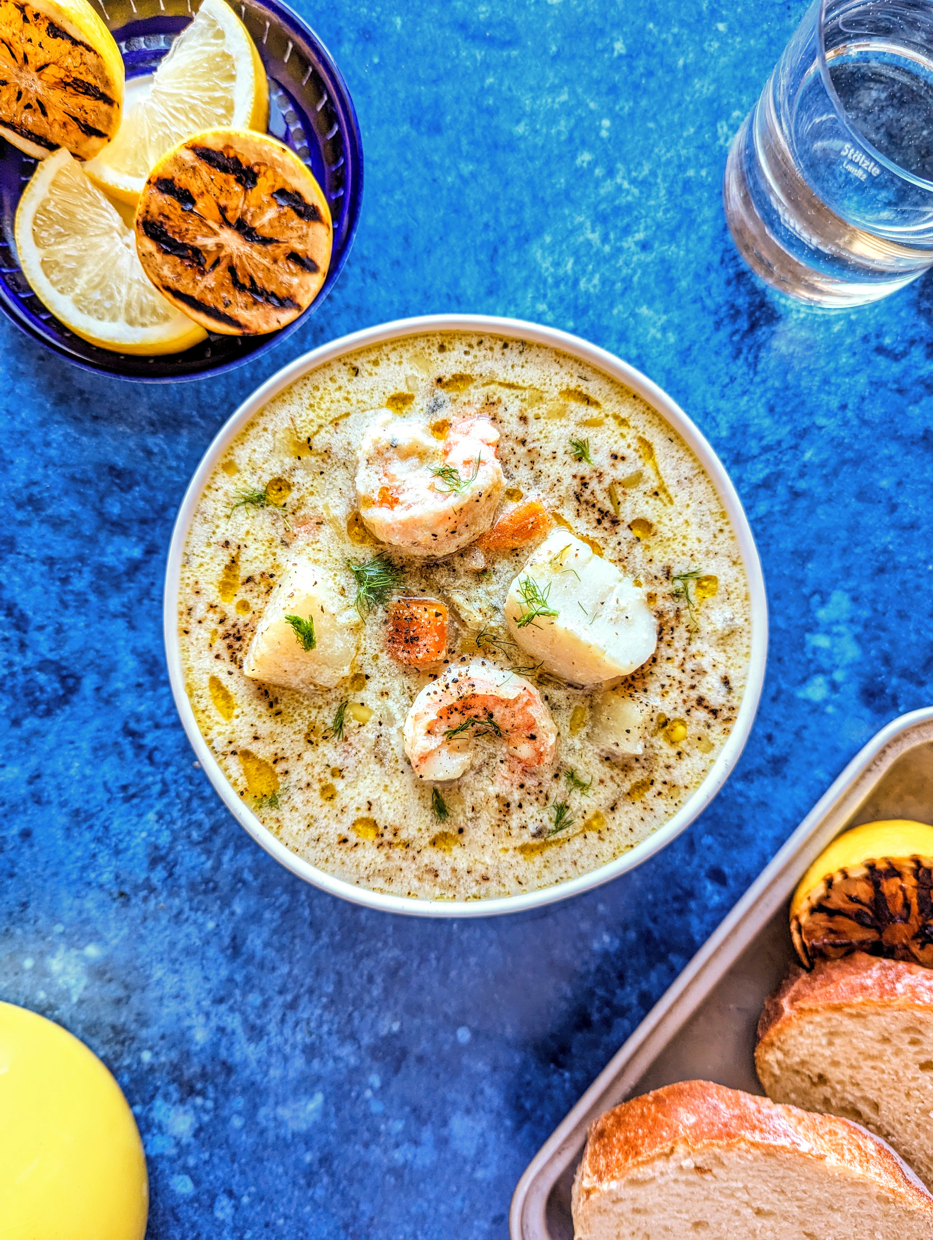 A bowl of hearty seafood chowder with grilled lemon and toasted bread.