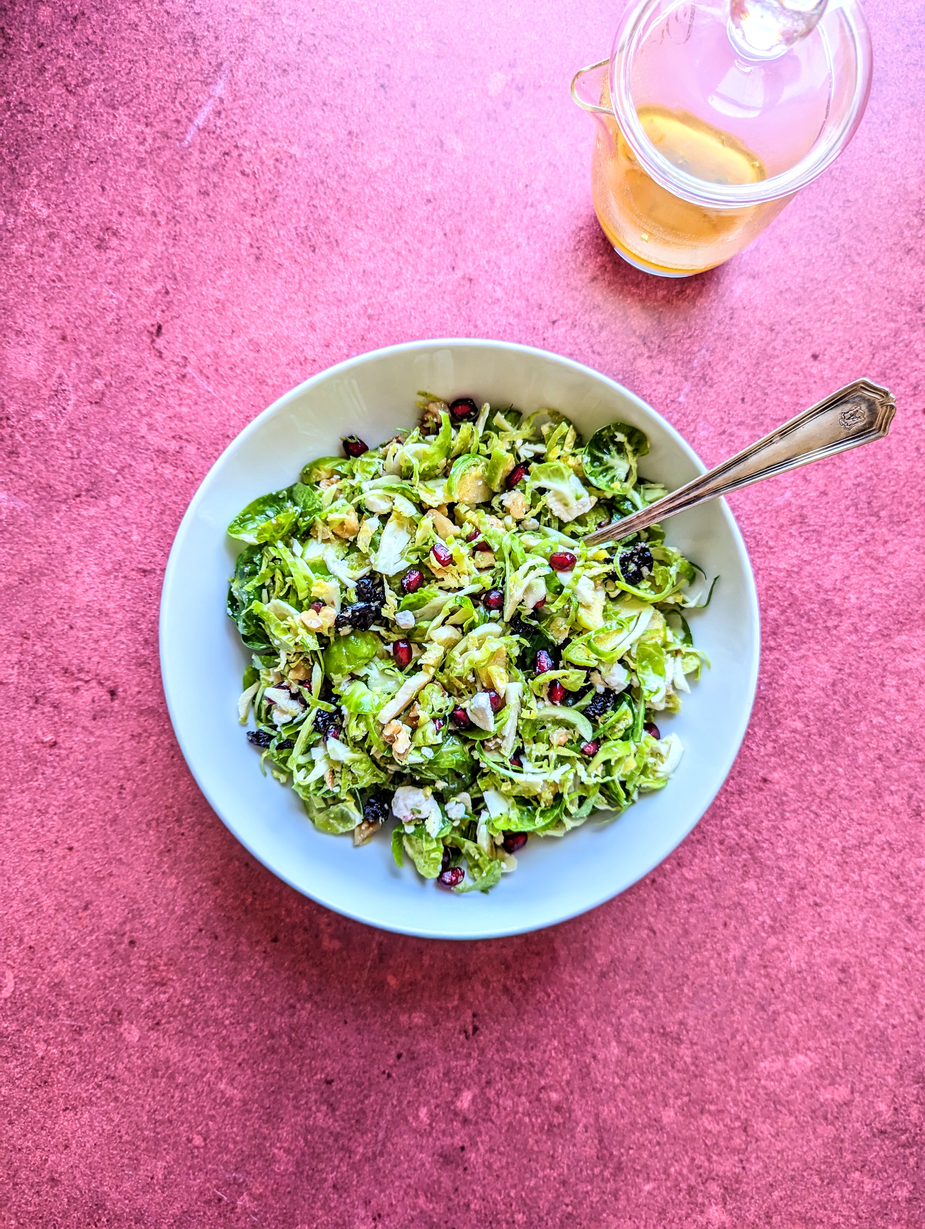 A bowl of Shaved Brussels Sprouts Salad over a deep red backdrop.