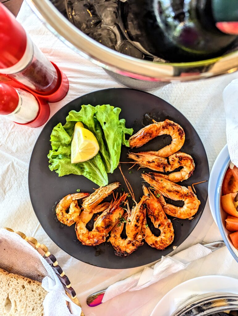 A plate of grilled shrimp served on a round black plate in Albania.