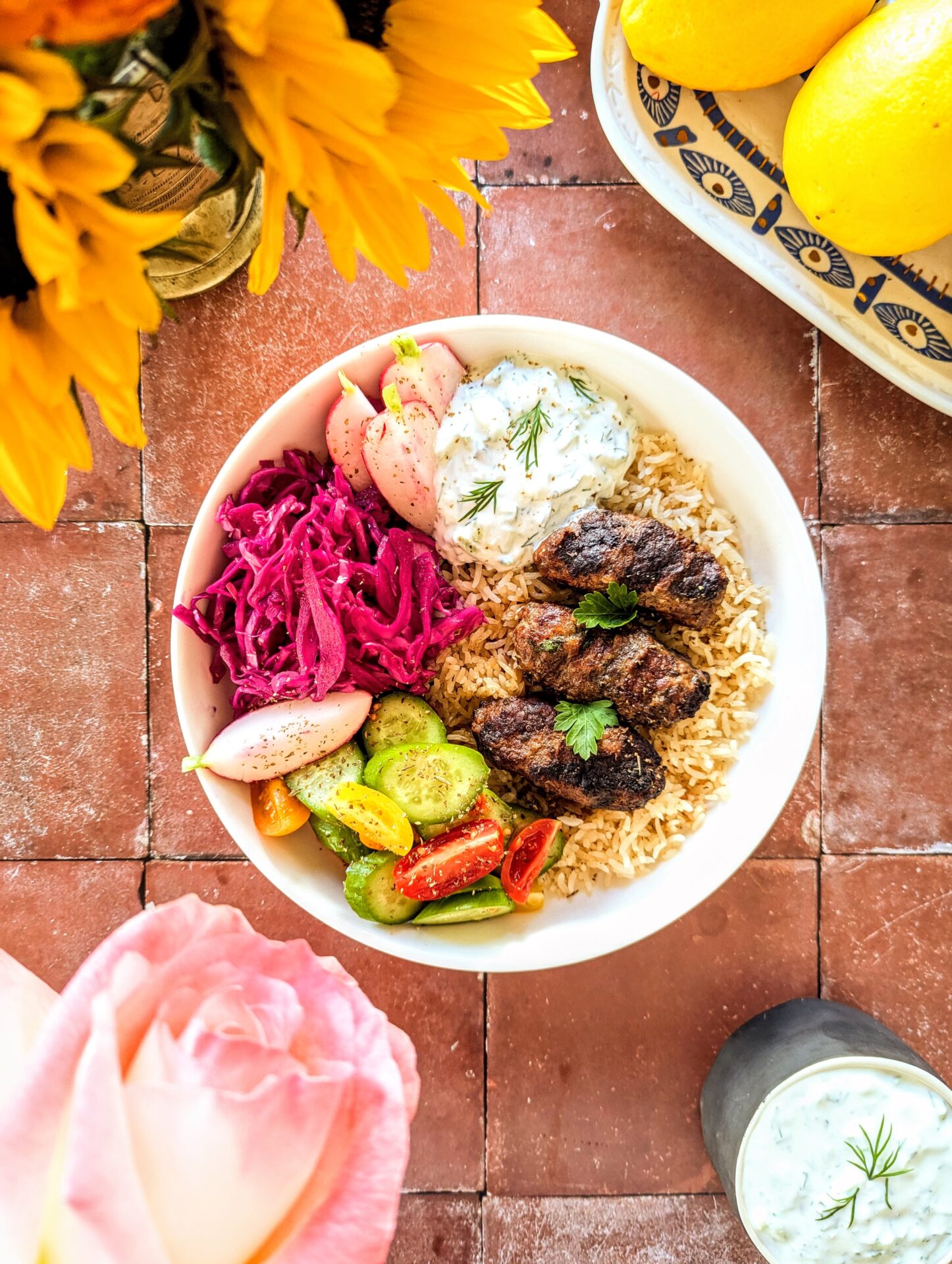 A vibrant platter featuring Kernacka Korçë, pilaf, pickled cabbage, a cool yogurt sauce, and simple salad.